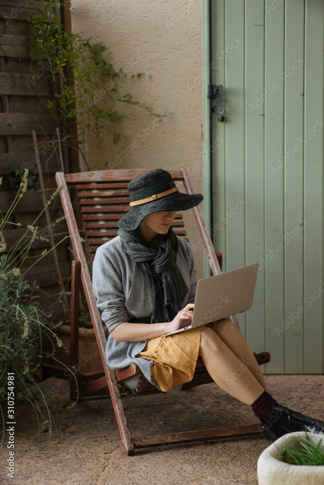 Person with laptop sitting on folding chair near wall Person with laptop sitting on folding chair near wall