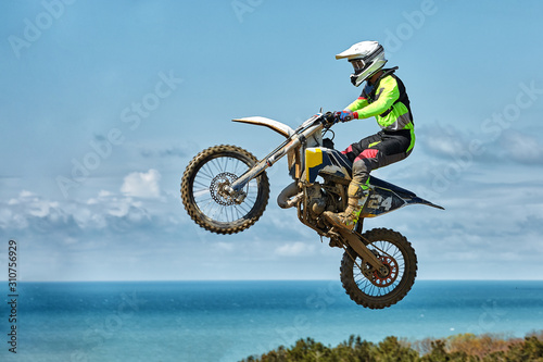 Fototapeta Naklejka Na Ścianę i Meble -  Extreme sports, motorcycle jumping. Motorcyclist makes an extreme jump against the sky. Film grain effect, illumination