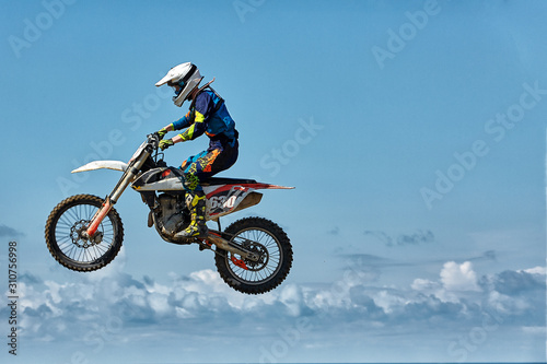 Extreme sports, motorcycle jumping. Motorcyclist makes an extreme jump against the sky. Film grain effect, illumination