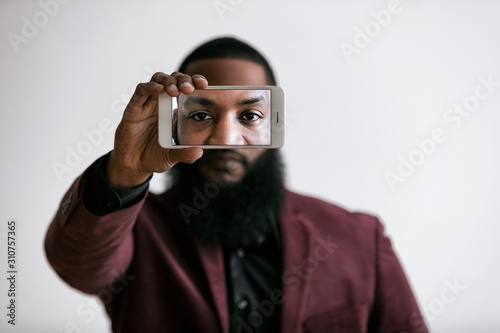 African American Male Holds Cell Phone In Front Of Eyes photo