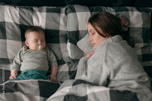 mother is sleeping with the baby on the bed photo