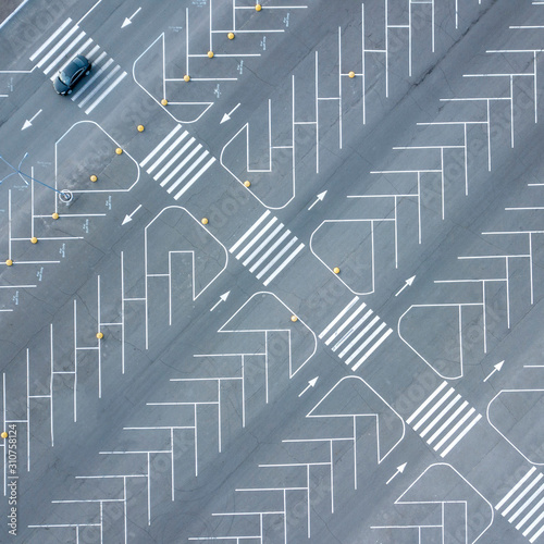 Diagonal road marking pattern from painted lines on a gray asphalt background. One moving car on parking. Aerial view from drone.