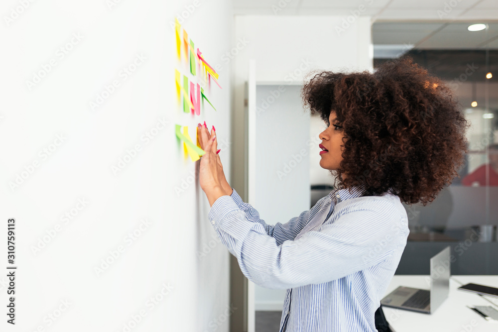 © Santi Nunez/Stocksy - Beautiful afro woman working at office © Santi Nunez/Stocksy - Beautiful afro woman working at office