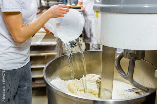 Baker Adding Water to a Professional Kneading Machine