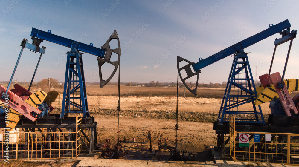 © Danil Nevsky/Stocksy - Oil pumpjacks over wells in evening