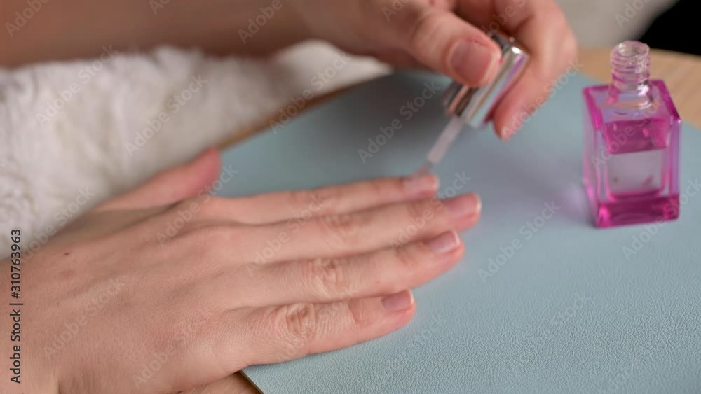 Girl does manicure at home. Transparent nail polish on female hands. Girl does manicure at home. Transparent nail polish on female hands.