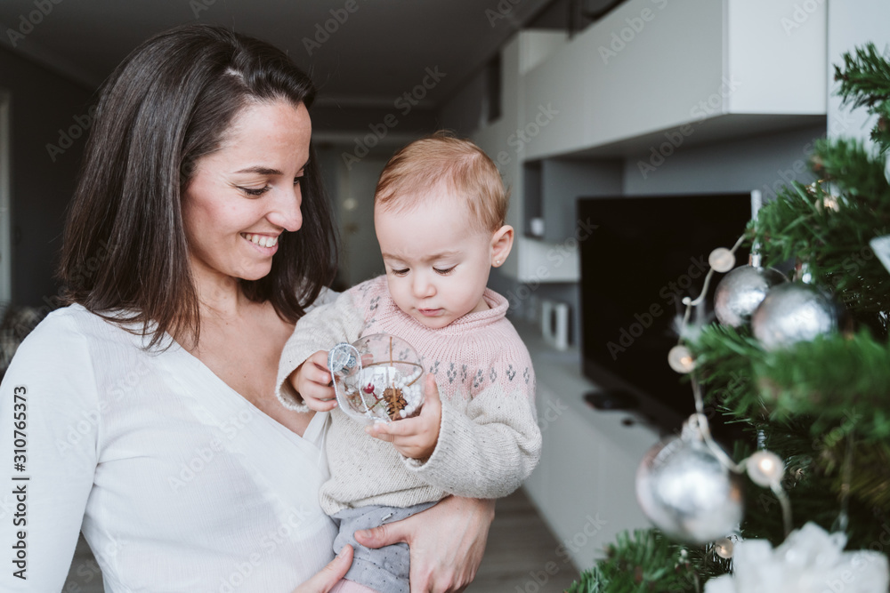 happy mother and baby girl decorating the Christmas tree happy mother and baby girl decorating the Christmas tree
