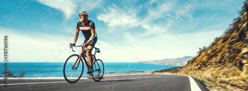 Mature Adult on a racing bike climbing the hill at mediterranean sea landscape coastal road photo