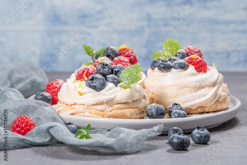 Mini pavlova meringue cakes with fresh raspberries and blueberries with mint leaves. photo