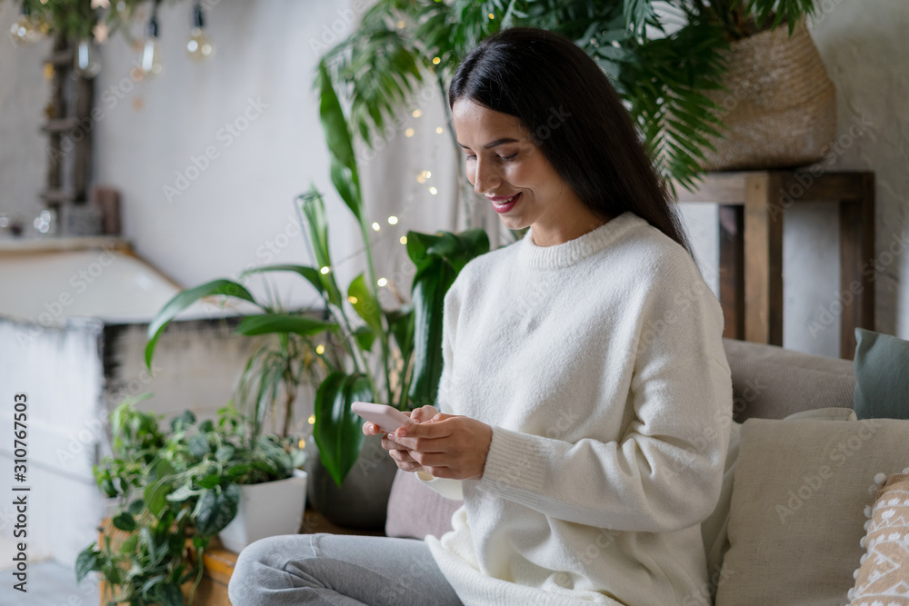 Calm young adult woman spending weekend at home using modern smartphone Calm young adult woman spending weekend at home using modern smartphone