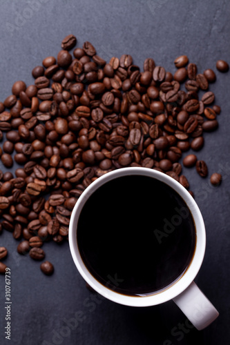 Roasted coffee beans and cup of coffee on granite background