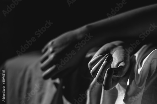 Close up on female young woman's girl's beautiful hands woman lying on the bed black and white nail polish in dark room crossed fingers on sheet gentle passion love temptation emotion concept photo