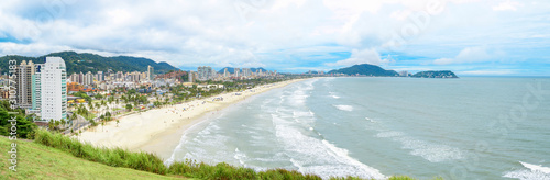 Panoramic aerial view of the Cove Beach at Guaruja SP Brazil. People on the beach, the sand, sea waves and the city on background. Place known as Praia da Enseada. Brazilian coastal city.