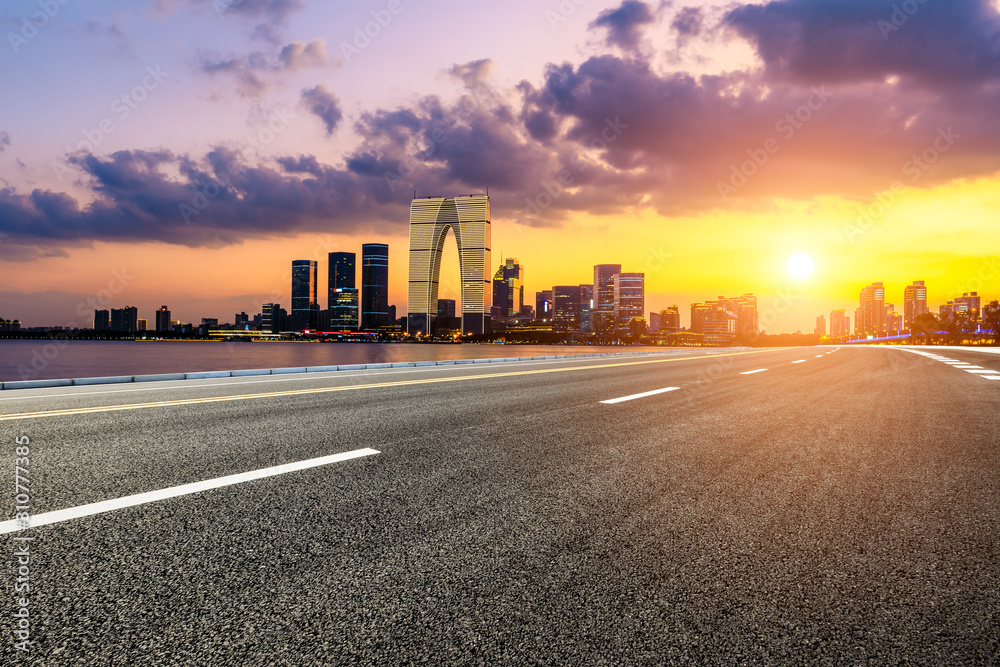 Fototapeta premium Asphalt road and Suzhou city skyline with beautiful colorful clouds at sunset.