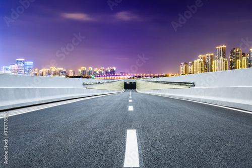 Asphalt road and Suzhou city skyline with beautiful colorful clouds at night.