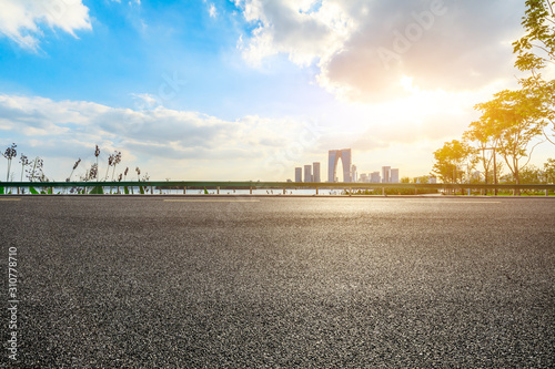 Asphalt road and Suzhou city skyline with beautiful clouds at sunset.