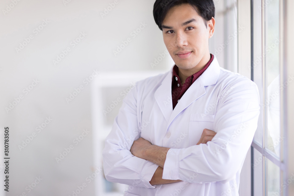 Asian scientists wear white robes standing by the window in the laboratory. And smiling at the camera Asian scientists wear white robes standing by the window in the laboratory. And smiling at the camera
