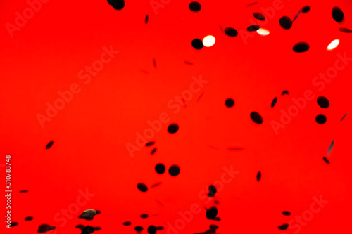 Black stylish falling confetti on red background. Holiday concept.