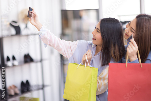 Two beautiful Asian women are shopping in the mall. And take pictures with the phone