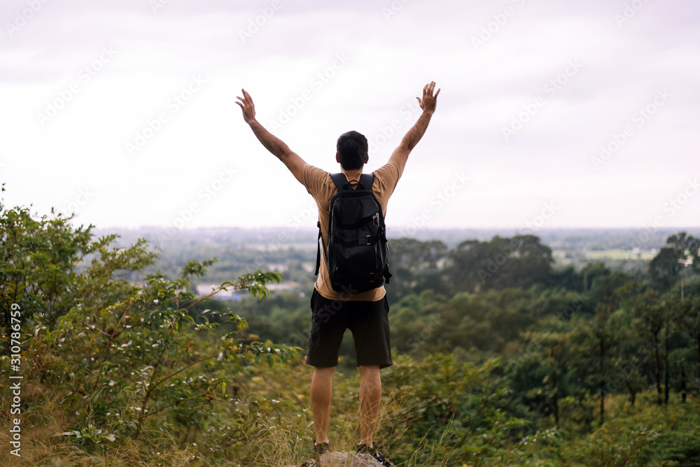 Tourist man with hands raised up and looking beautiful view feeling happy and smiling at nature,Back view Tourist man with hands raised up and looking beautiful view feeling happy and smiling at nature,Back view
