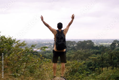 Tourist man with hands raised up and looking beautiful view feeling happy and smiling at nature,Back view