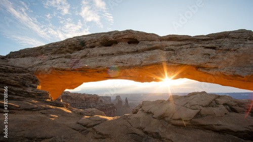 Mesa Arch glowing as the sun shines over the desert at sunrise in Canyonlands.