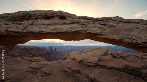 Mesa Arch as the sun starts to rise lighting up the clouds at dawn.