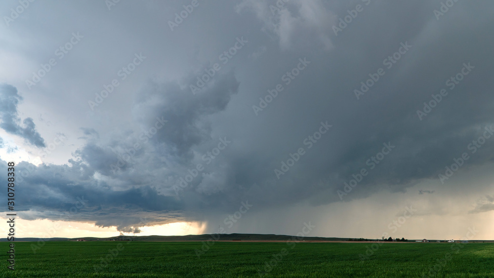 Tornado touching ground behind rainstorm in Nebraska in wide view of severe storm.