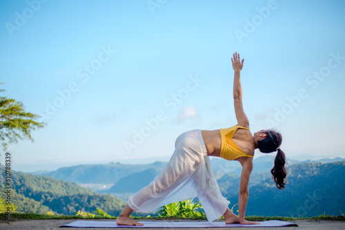 Side view of healthy women practicing yoga. doing Ashtanga Vinyasa yoga asana Utthita trikonasana pose , beautiful landscape nature view, concept for exercising, health care.