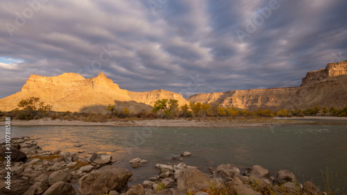 Sunlight shining through the clouds on desert landscape of Grays Canyon as the Green River flows past Swasey's Beach.