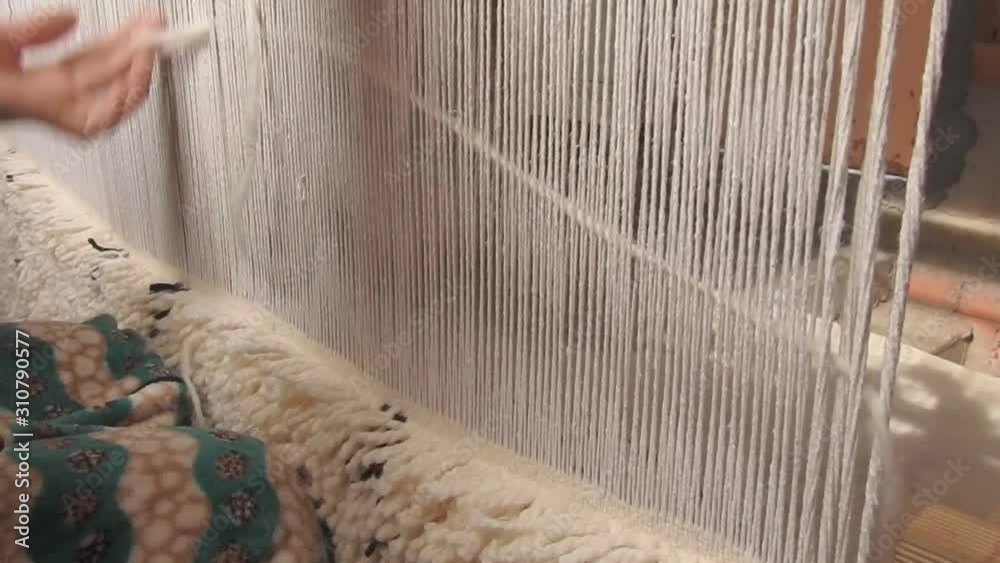 close up on a Moroccan girl weaving a carpet with a manual waving machine, Carpet weaving , Needlework , Morocco .