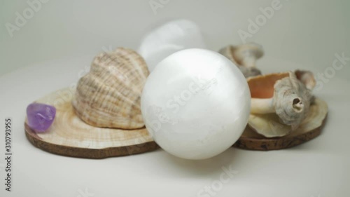 Sea Shells Sitting On Top Of A Wooden Craft With Two Crystal Balls And Small Gem Stones In Between - Close Up Shot photo