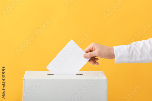 Voting woman near ballot box on color background photo