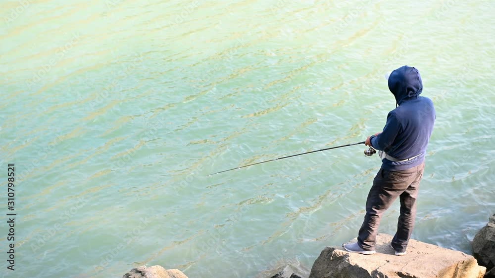 man standing and fishing on the edge of a river man standing and fishing on the edge of a river