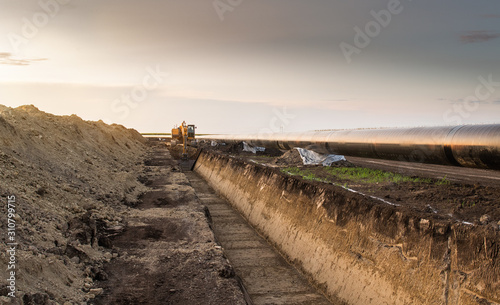 Crane digging a channel for gas pipeline