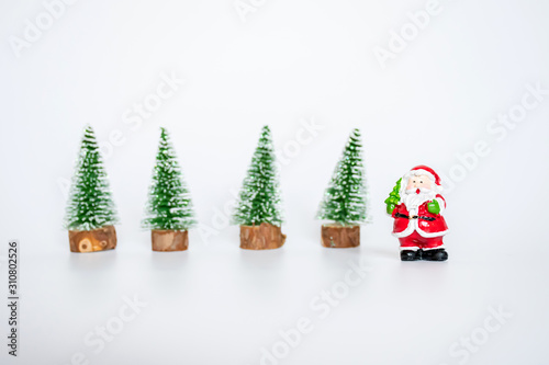 Objects, small santa clausu statue with bakcground small artifician Christmas tree on nature wooden table  on white background, decorate christmas concept. photo
