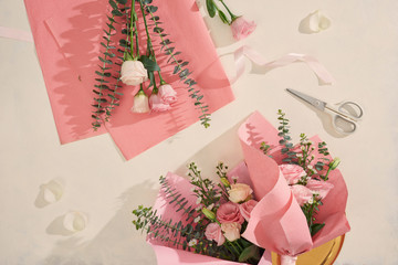 Making pink flowers bouquets with scissor on white background. Holiday, mothers day, valentine day concept. Top view, flatlay