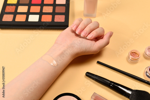 Foundation on woman hand. Professional makeup products with cosmetic beauty products  foundation  lipstick   eye shadows  brushes and tools.