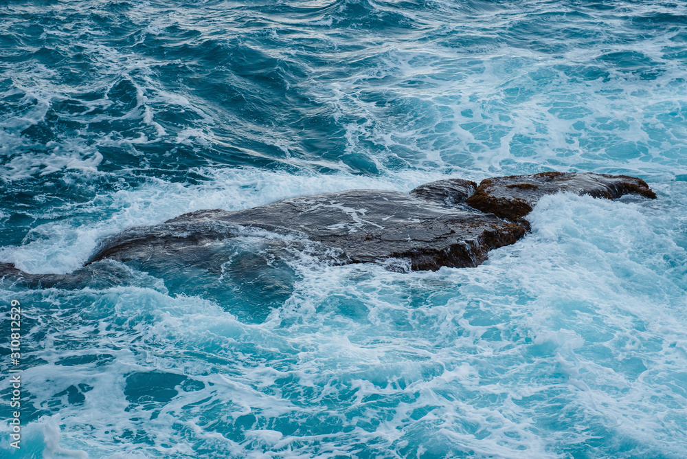 Naklejka premium Closeup of sea waves with white foam. The waves wash the stone