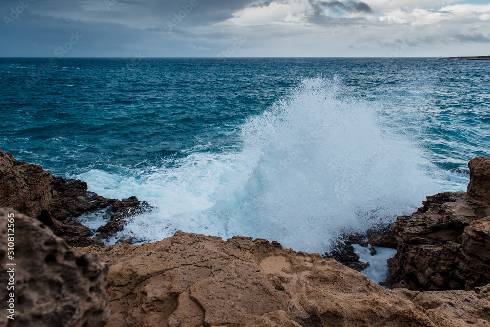 Restless turquoise sea in Cyprus, Cape Greco. The waves crash into the rocky shore