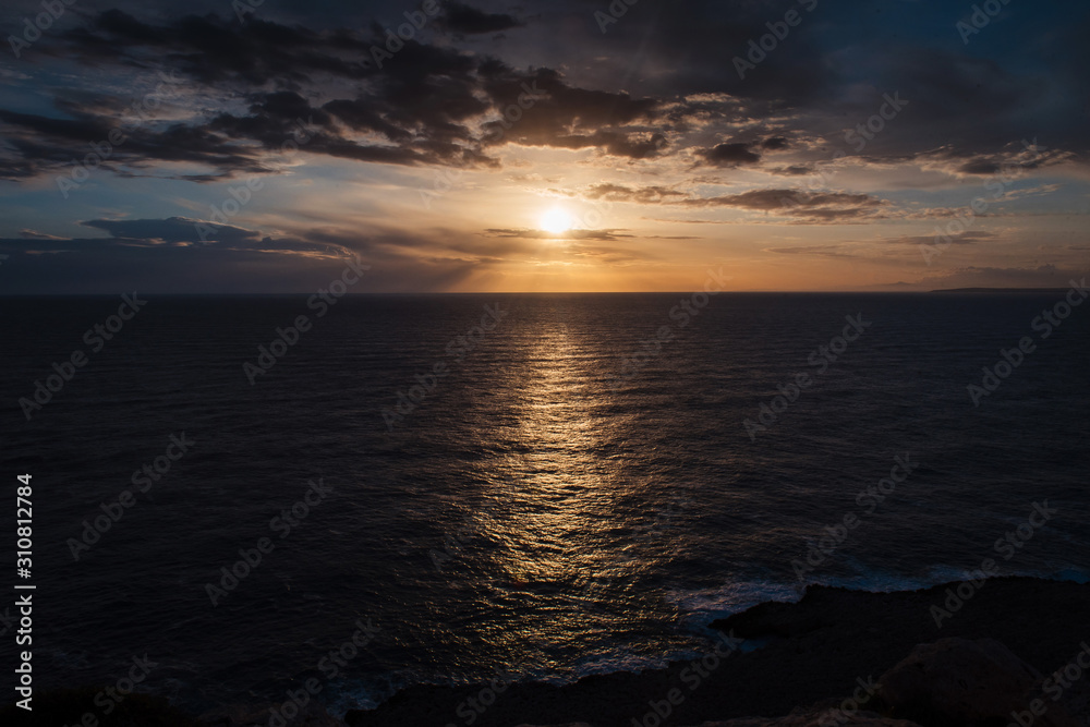 Obraz premium Wonderful sunset. Calm dark sea and golden sky with clouds
