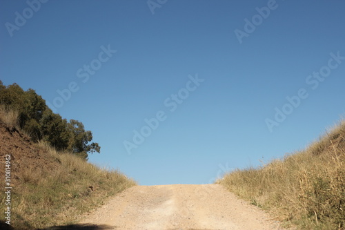 wide shot of long dirt dusty country road leading off into the distance on dry arid drought stricken agricultural farm land  rural New South Wales  Australia