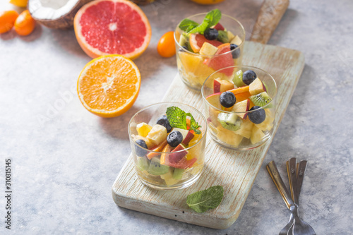 Fruit salad in glasses,  fresh summer foods , healthy organic orange kiwi blueberries pineapple coconut. top view