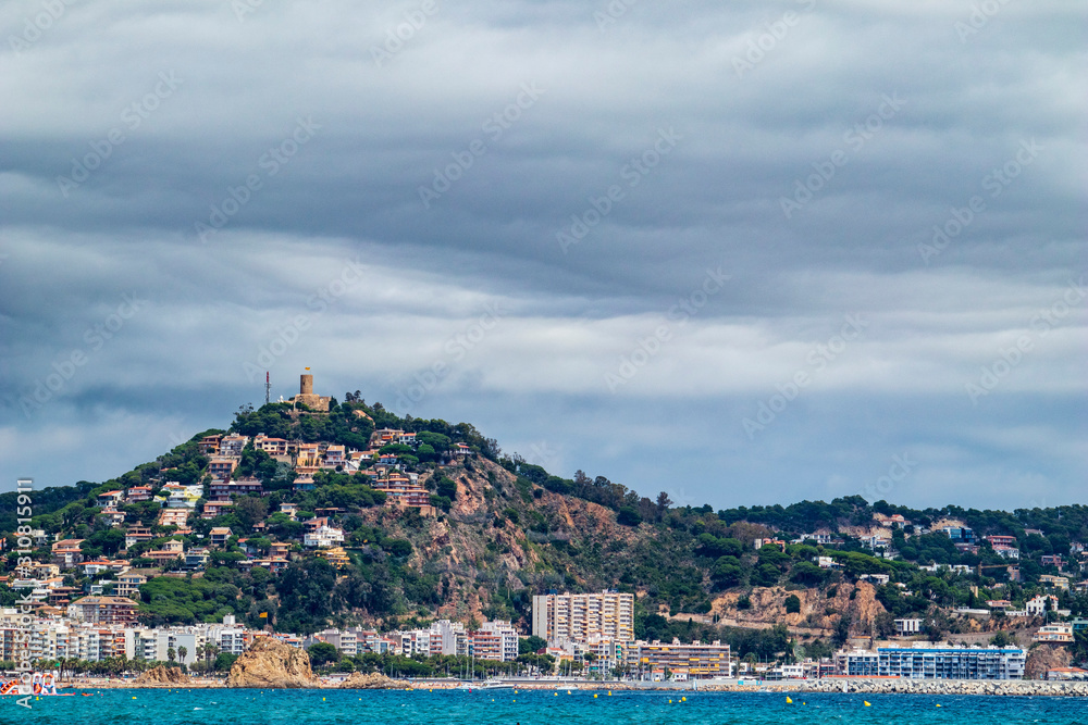 Blanes Castle, from the beach, with clouds threatening rain