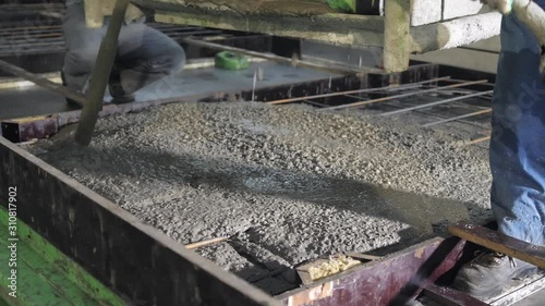 A large radio-controlled machine fills the concrete in form. Workers in the workshop of the House-building plant. Industrial interior. Concrete plant.