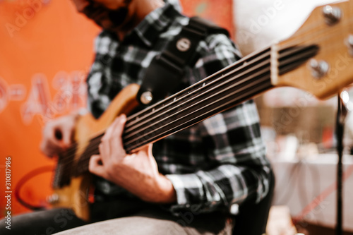 Photo of musician playng on six string fretless bass guitar on the street in front of people.