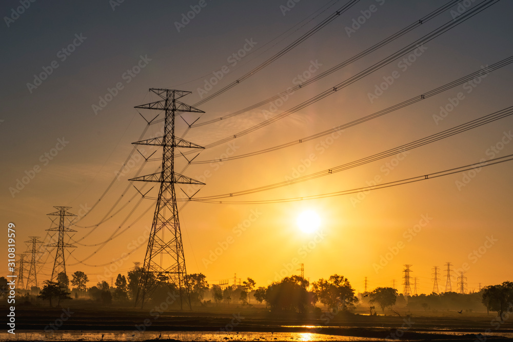 Electric pole and electric cable on the field in the countryside with Sunrise sky.