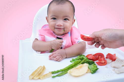 Tableau sur toile Cute Asian baby girl eating by hands, Little baby eating organic vegetables with
