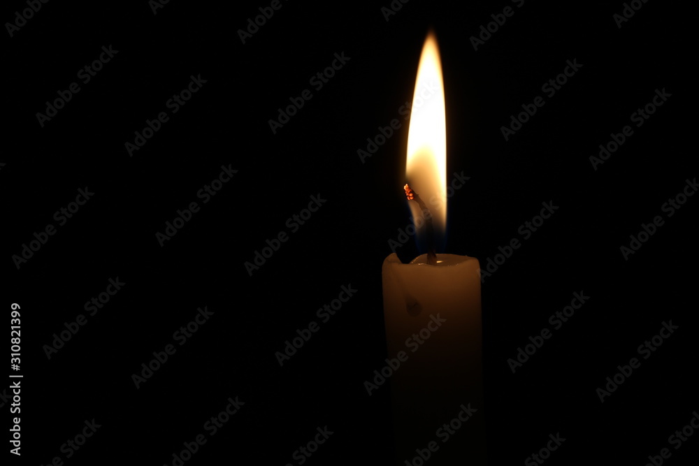 One light candle burning brightly in the black background One light candle burning brightly in the black background