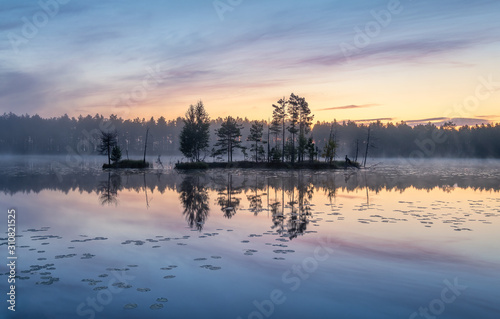 Beautiful sunrise landscape with misty mood and calm lake at foggy summer morning in Finland